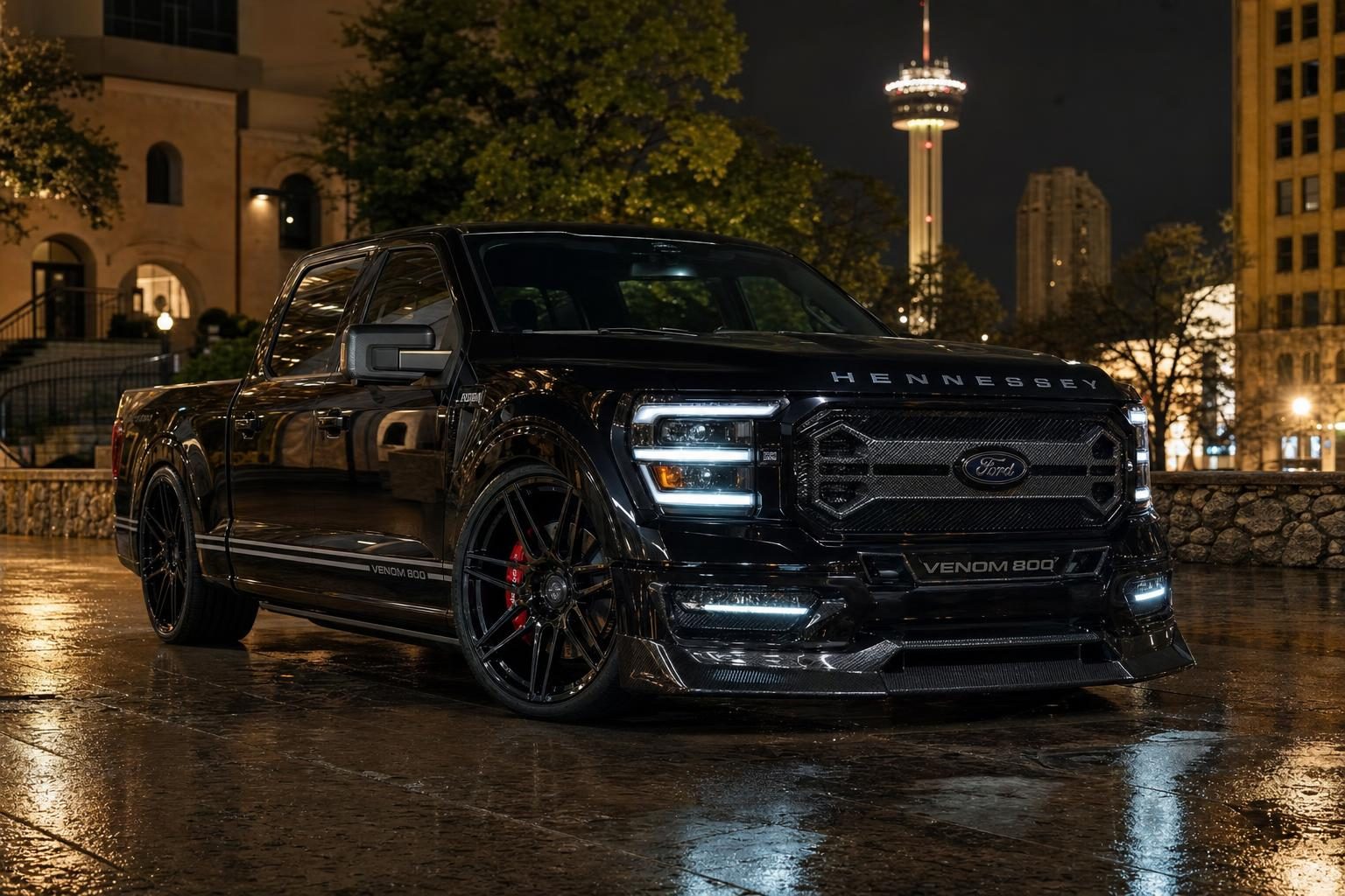 Black Hennessey Venom 800 Lowered Ford F-150 crew cab on a wet downtown San Antonio street at night with the Tower of the Americas